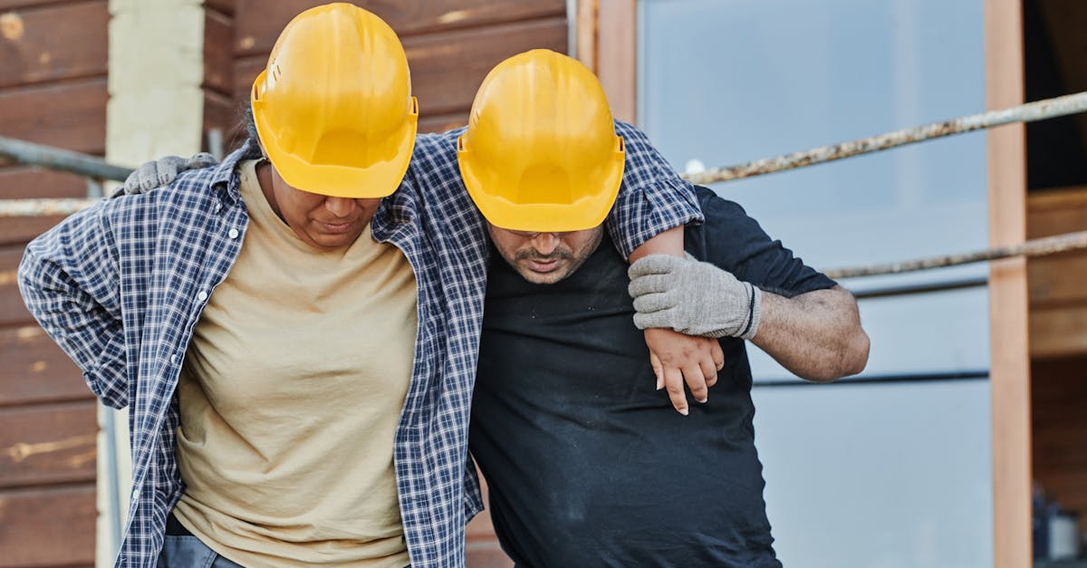 Trabalhador da construção civil com capacete amarelo sendo ajudado por colega após sentir dor ou lesão. — Foto: Mikael Blomkvist