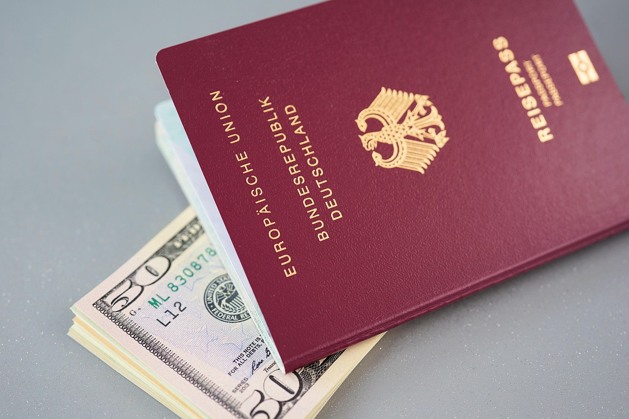 Passaporte europeu bordô sobre um maço de notas de dólares americanos em fundo cinza. — Foto: webandi