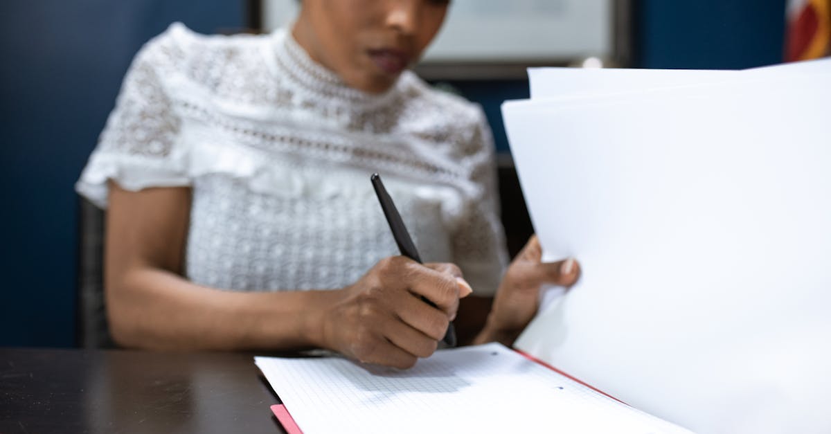 Mulher negra com blusa branca de renda assinando documentos em uma mesa de escritório. — Foto: RDNE Stock project
