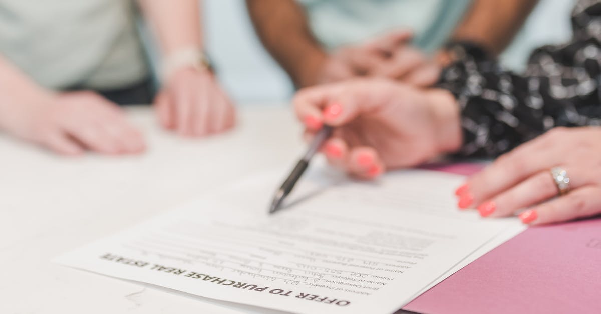 Mãos segurando uma caneta sobre um documento de oferta de compra de imóvel em uma mesa. — Foto: RDNE Stock project