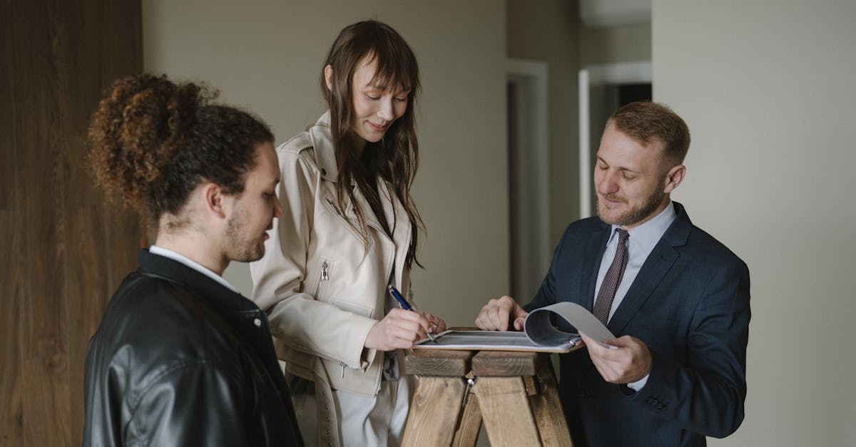 Mulher assinando contrato em prancheta enquanto homem de terno observa e outro homem acompanha a transação. — Foto: Anastasia Shuraeva