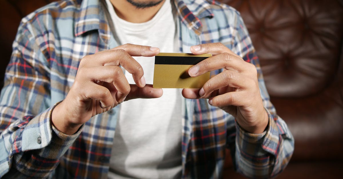 Homem segurando e analisando um cartão de crédito dourado com as duas mãos. — Foto: Towfiqu barbhuiya