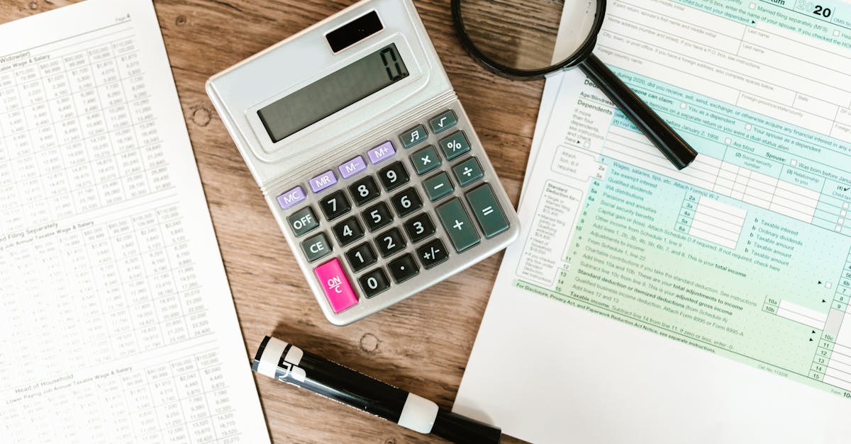 Calculadora branca, lupa e caneta sobre formulários financeiros e planilhas em uma mesa de madeira. — Foto: RDNE Stock project
