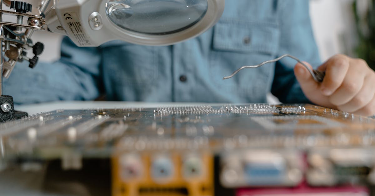 Pessoa utilizando lupa de bancada para analisar componentes eletrônicos em uma placa de circuito. — Foto: MART PRODUCTION