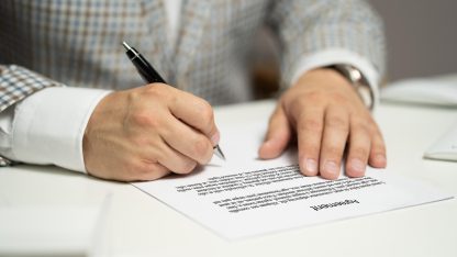 Commercial litigation in brazil 85664 1777122506 Close das mãos de um homem de terno assinando um documento de contrato sobre uma mesa branca. — foto: tumisu