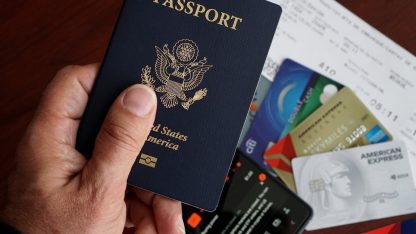 Mão segurando um passaporte americano sobre diversos cartões de crédito e documentos de viagem. — Foto: DΛVΞ GΛRCIΛ