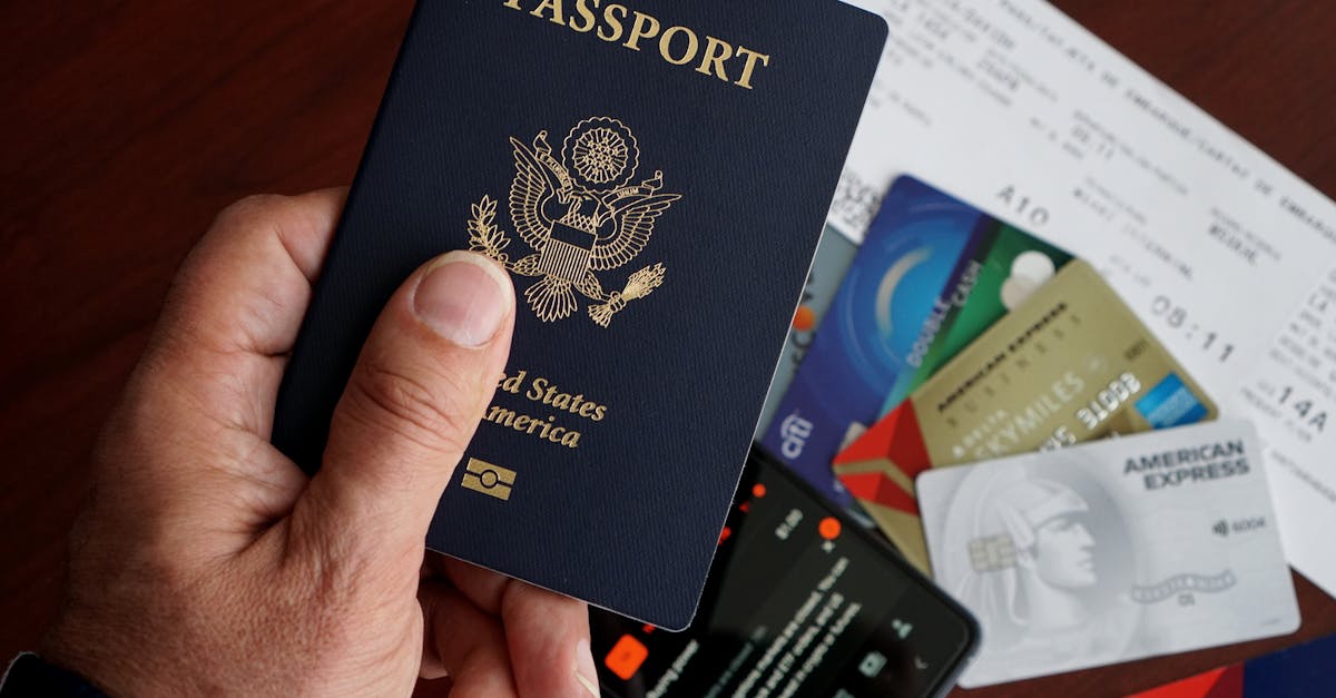 Mão segurando passaporte dos Estados Unidos sobre mesa com cartões de crédito e passagens aéreas. — Foto: DΛVΞ GΛRCIΛ