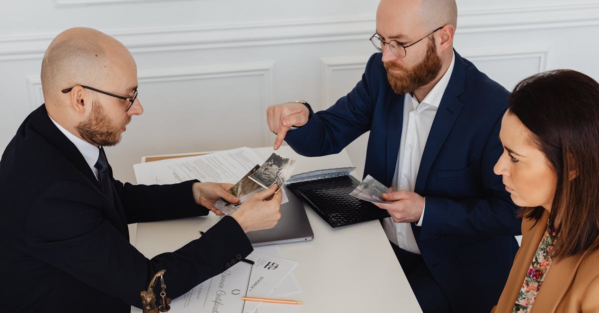 Advogados em reunião analisando fotografias e documentos sobre uma mesa branca em escritório. — Foto: www.kaboompics.com