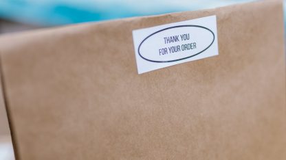 Close em uma embalagem de papel pardo com etiqueta de agradecimento pelo pedido. — Foto: RDNE Stock project