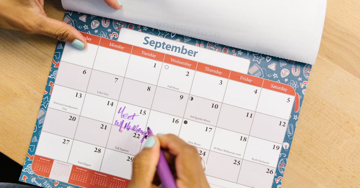 Ferias 83968 1775833459 Mão de uma pessoa marcando datas com uma caneta roxa em um calendário de mesa sobre uma superfície de madeira. — foto: rdne stock project