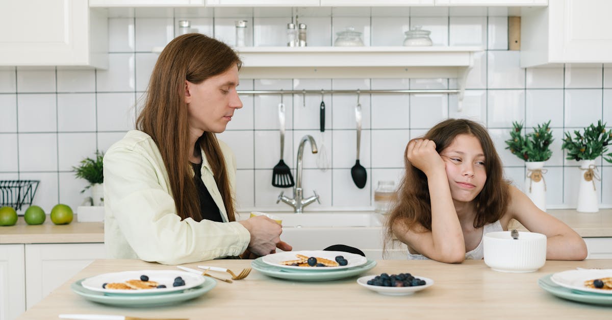 Homem e criança sentados à mesa de cozinha com expressão de desânimo e distanciamento durante o café da manhã. — Foto: Mikhail Nilov