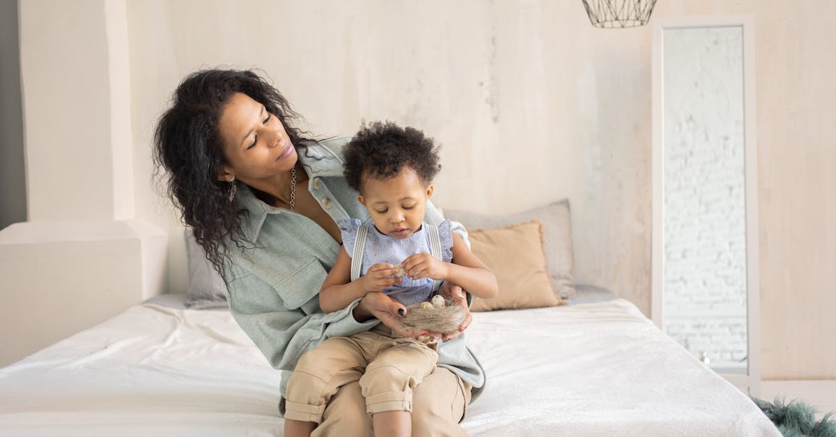 Mulher sentada em uma cama segurando uma criança pequena no colo em um ambiente iluminado. — Foto: KATRIN BOLOVTSOVA