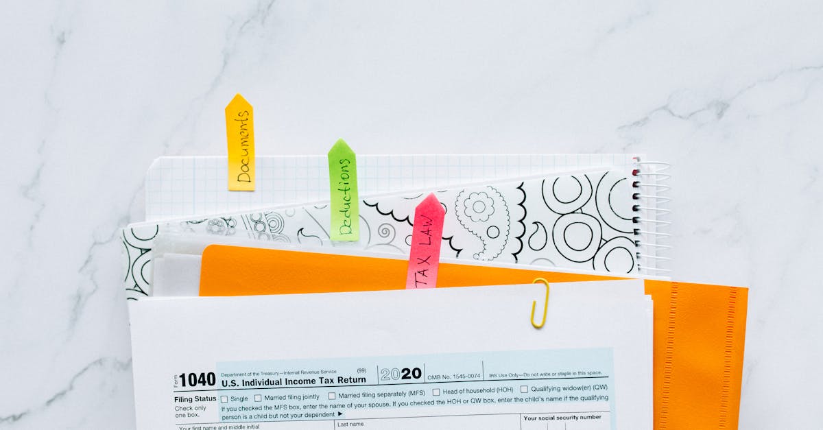Documentos de declaração de imposto com etiquetas coloridas organizados sobre uma mesa de mármore branca. — foto: nataliya vaitkevich