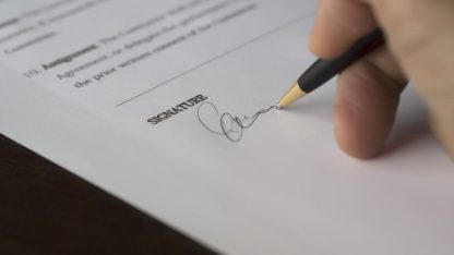 Close de uma mão segurando uma caneta e assinando um documento oficial sobre a linha de assinatura. — Foto: Pixabay