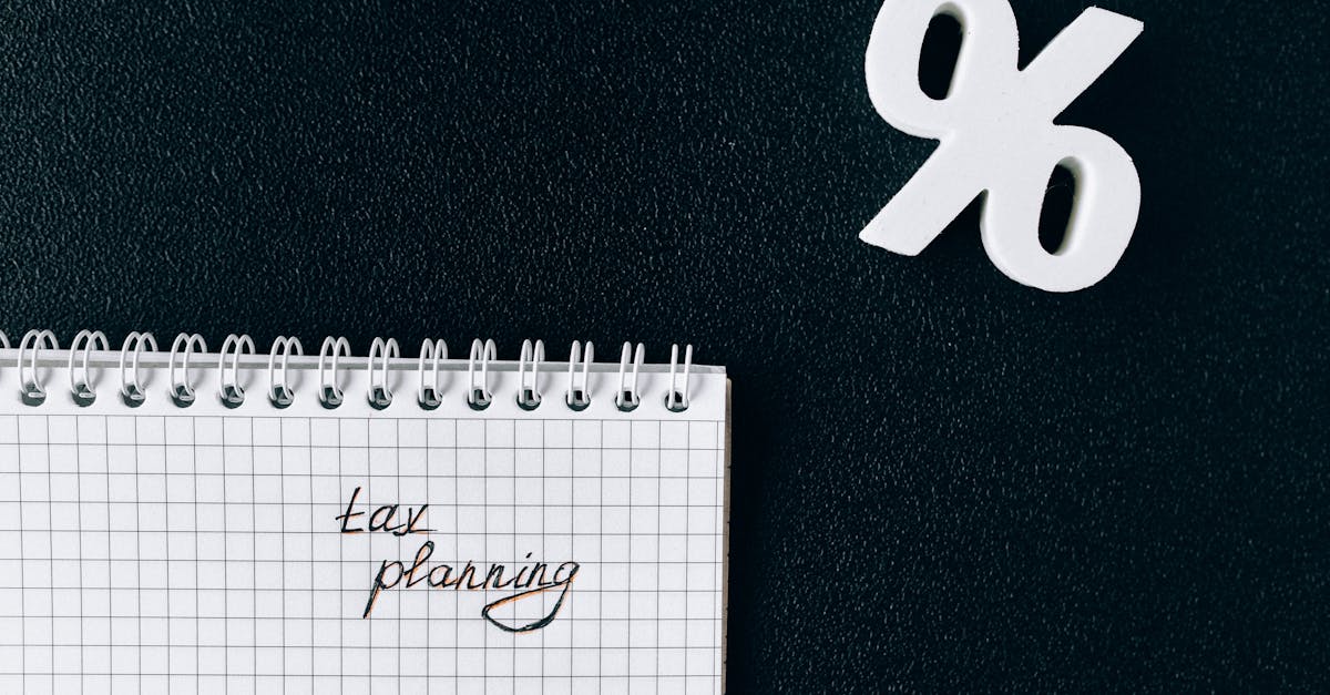 Bloco de notas com a escrita 'tax planning' ao lado de um símbolo de porcentagem branco sobre fundo escuro. — Foto: Nataliya Vaitkevich
