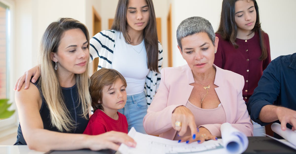 Uma advogada e uma família reunida em volta de uma mesa analisando documentos e plantas de imóveis. — Foto: Kampus Production