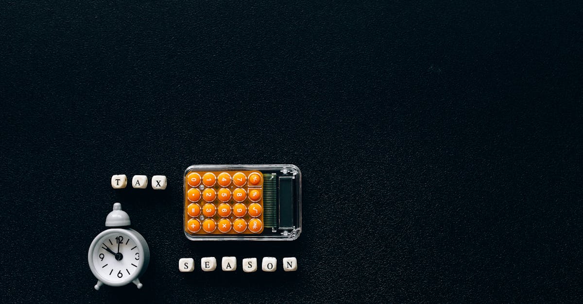 Calculadora laranja, despertador branco e blocos com a palavra TAX sobre fundo preto. — Foto: Nataliya Vaitkevich