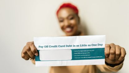 Mulher sorridente segurando um envelope sobre pagamento de dívidas de cartão de crédito. — Foto: RDNE Stock project