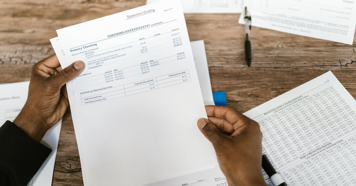 Mãos de uma pessoa segurando e analisando faturas e documentos financeiros sobre uma mesa de madeira. — Foto: RDNE Stock project