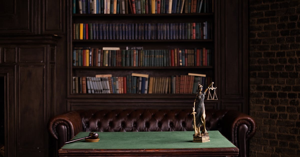 Estátua da Justiça e martelo de juiz sobre mesa verde em escritório de advocacia com estante de livros ao fundo. — Foto: KATRIN BOLOVTSOVA