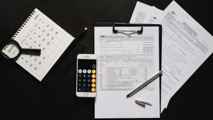 Vista superior de formulários de impostos em uma prancheta, smartphone com calculadora, caneta e calendário sobre mesa. — Foto: Leeloo The First