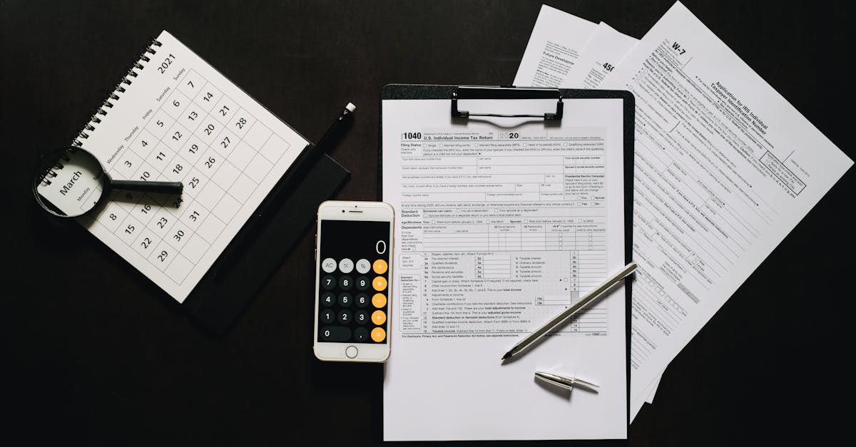 Vista superior de formulários de impostos em uma prancheta, smartphone com calculadora, caneta e calendário sobre mesa. — Foto: Leeloo The First