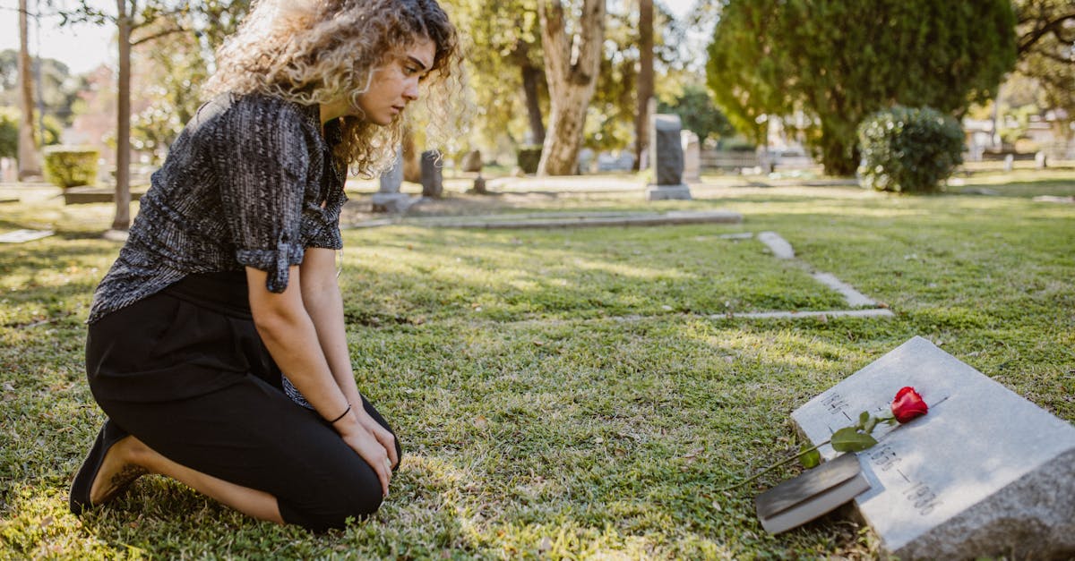 Pensao por morte 84092 1775919931 Mulher ajoelhada em frente a uma lápide em um cemitério com uma rosa vermelha sobre o túmulo. — foto: rdne stock project