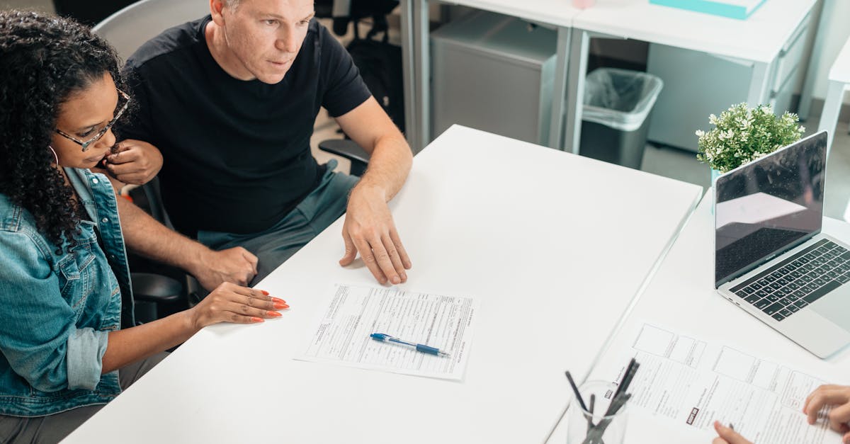 Homem e mulher sentados à mesa de escritório analisando um formulário de papel com uma caneta. — Foto: Kindel Media