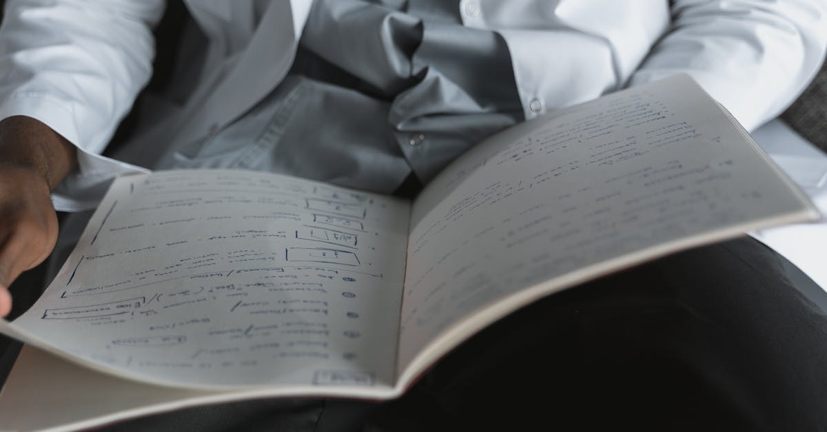 Pessoa vestindo jaleco ou camisa social branca segurando e lendo um caderno com anotações e diagramas. — Foto: Tima Miroshnichenko