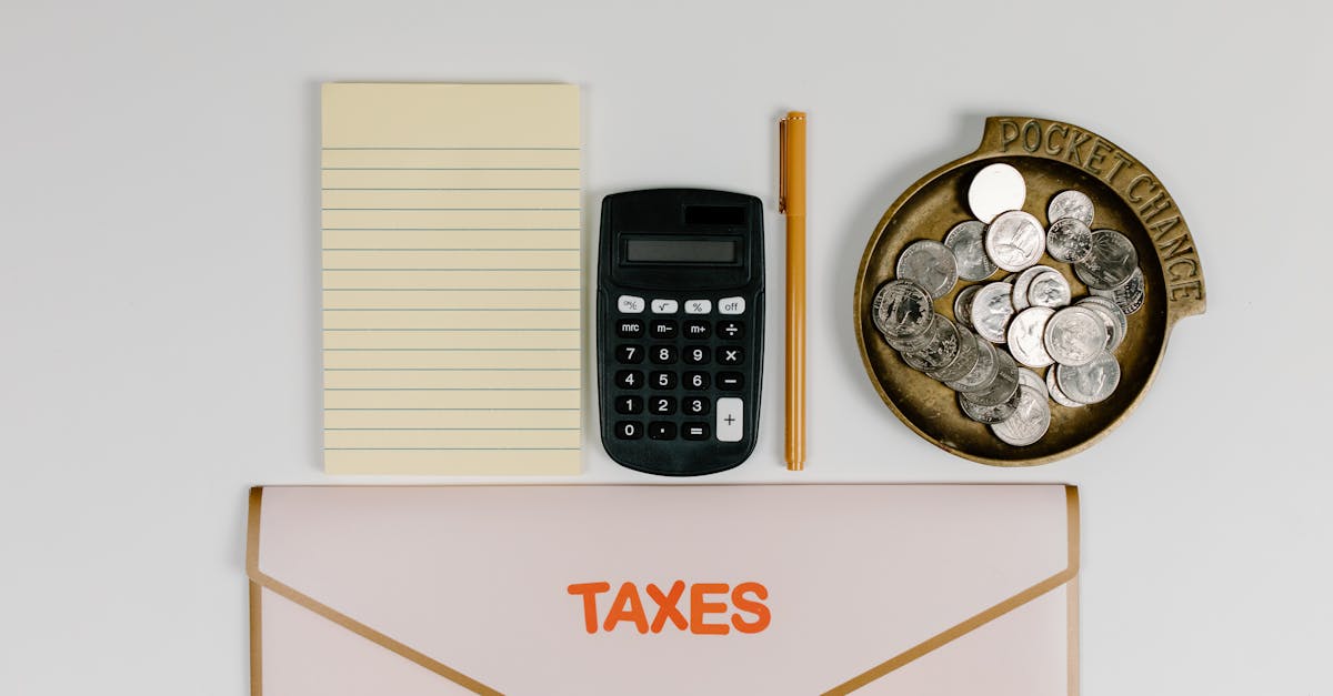Calculadora, bloco de notas, moedas e uma pasta com a palavra Taxes organizada sobre uma mesa branca. — Foto: Tara Winstead