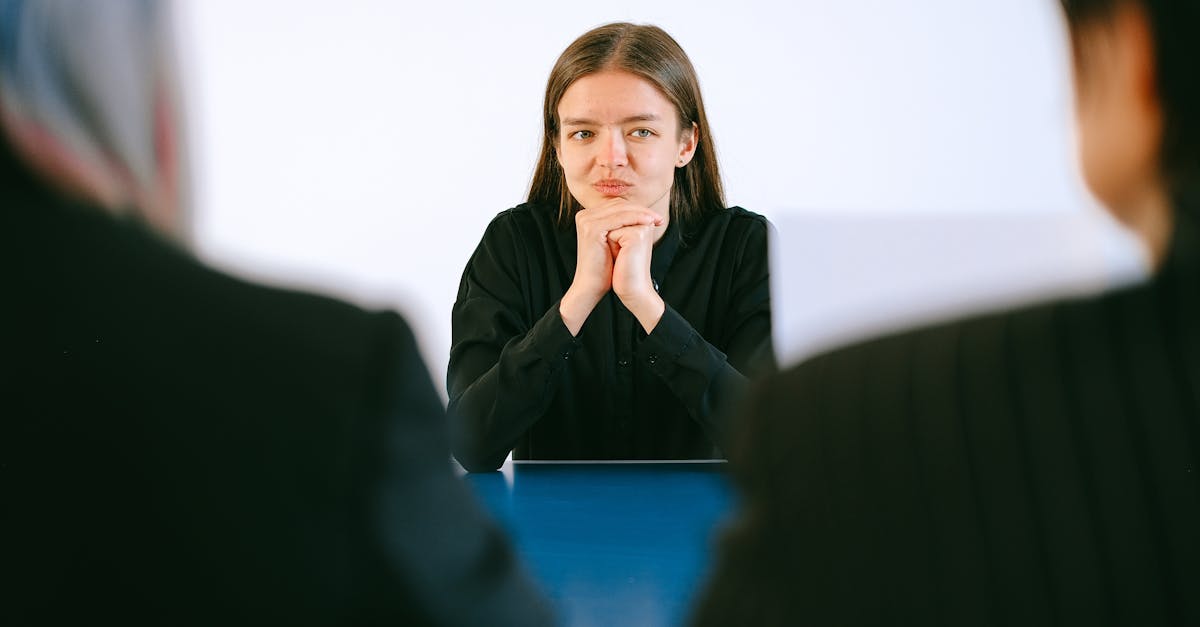 Mulher jovem sentada à mesa em reunião profissional, vista por trás de dois interlocutores em um escritório. — Foto: Anna Shvets