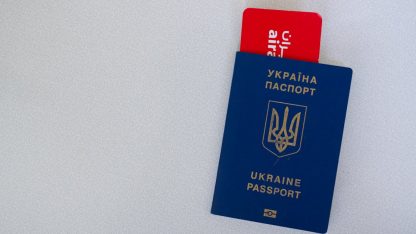 Um passaporte azul da Ucrânia com um cartão de embarque vermelho inserido, sobre um fundo branco. — Foto: Borys Zaitsev