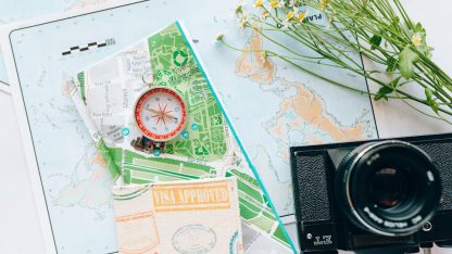Passaporte com carimbo de visto aprovado sobre mapas turísticos ao lado de uma bússola e câmera fotográfica. — Foto: Nataliya Vaitkevich