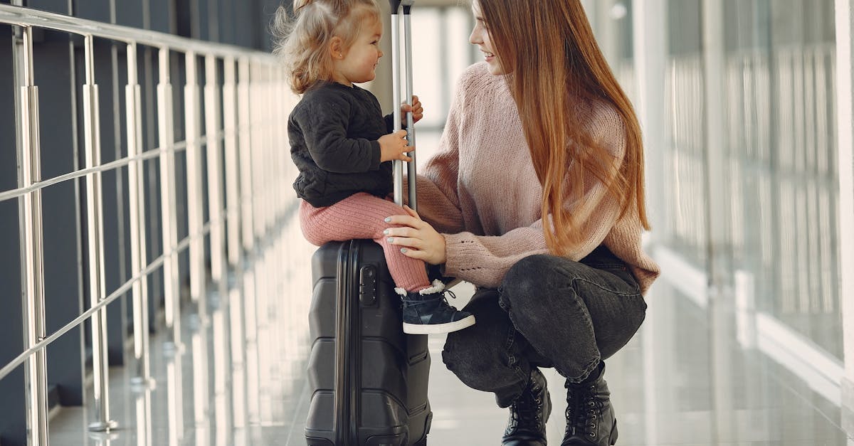 Mãe agachada conversando com criança pequena sentada sobre uma mala de viagem em um aeroporto. — Foto: Gustavo Fring