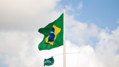 Bandeira do Brasil hasteada em um mastro sob um céu azul com nuvens brancas. — Foto: Tallita Maynara