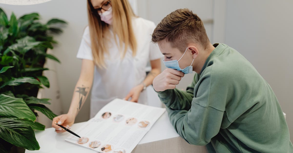 Profissional de saúde com máscara aponta para documentos enquanto atende um jovem em um consultório ou escritório. — Foto: www.kaboompics.com