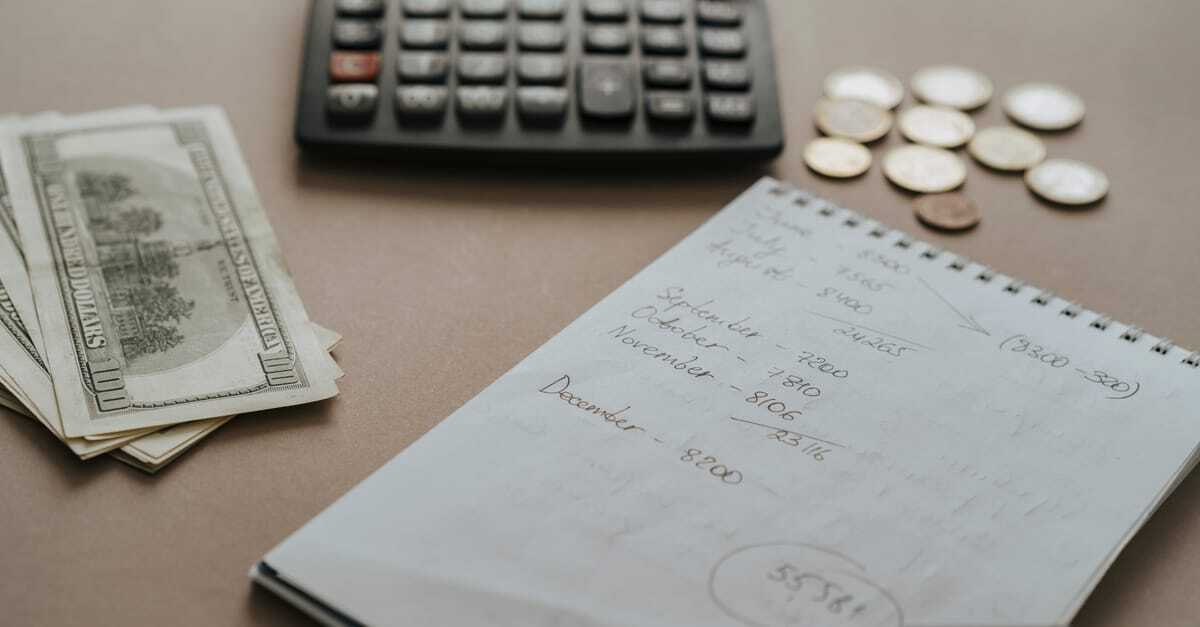 Calculadora, notas de dinheiro e um bloco de notas com anotações financeiras sobre uma mesa. — Foto: olia danilevich