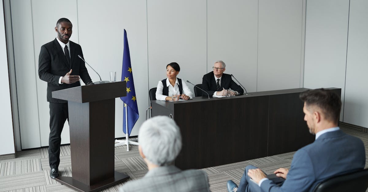 Homem em terno discursando em frente a um painel de juristas em uma sala de conferências. — Foto: Werner Pfennig