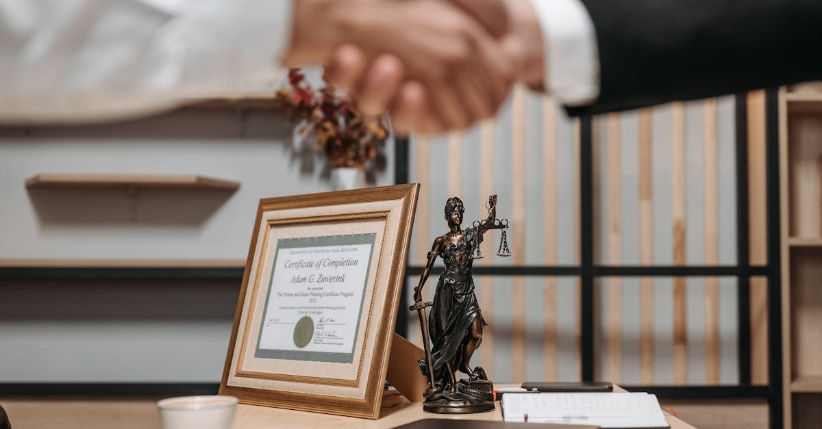 Profissionais em reunião de negócios, com uma estátua de justiça e documentos em uma mesa. — Foto: Pavel Danilyuk