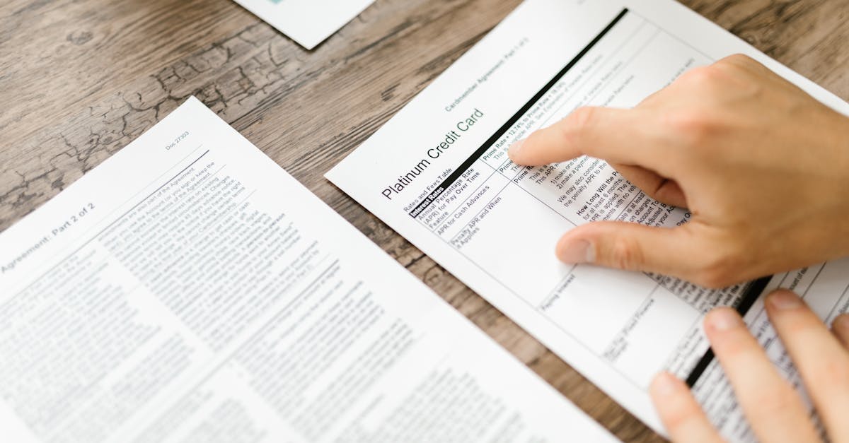 Mãos de uma pessoa lendo e apontando para um documento de contrato sobre uma mesa de madeira. — Foto: RDNE Stock project
