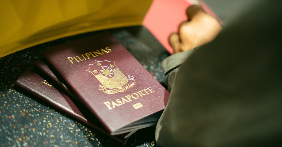 Pessoas com passaportes filipinos em uma mesa, uma pessoa escrevendo em um documento. — Foto: Kenneth Surillo