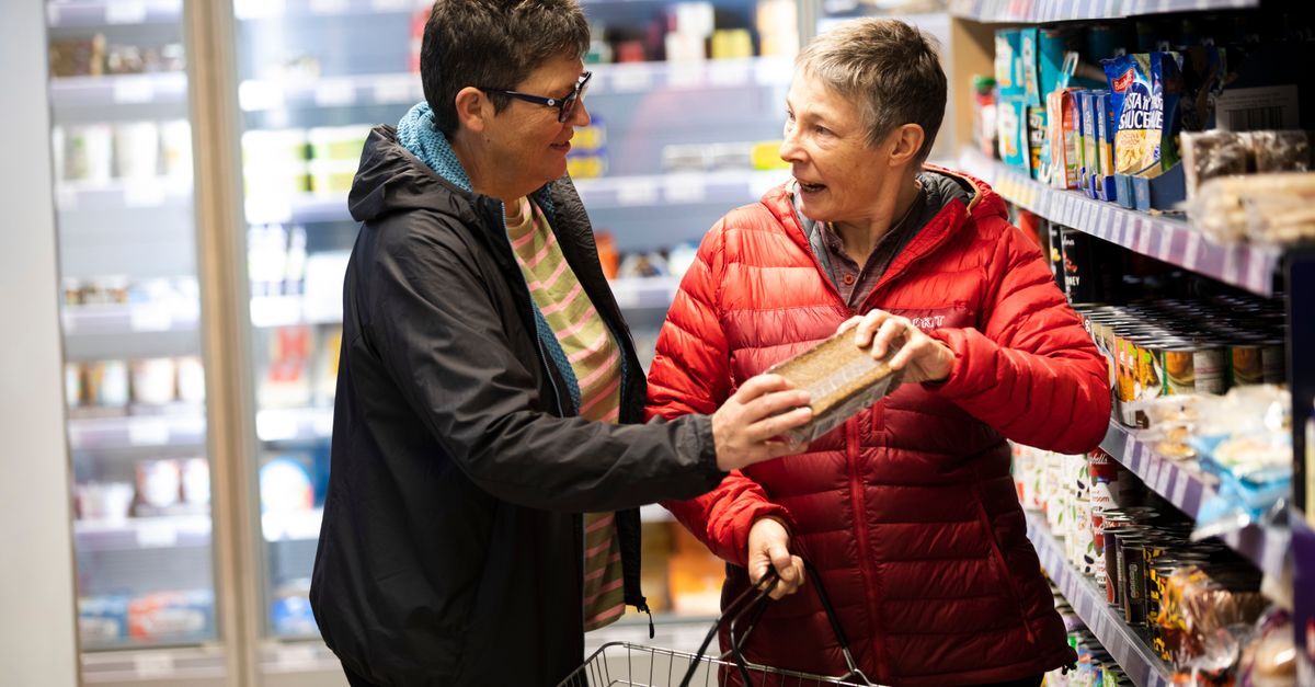 Duas mulheres conversando enquanto escolhem produtos em uma prateleira de supermercado. — Foto: Centre for Ageing Better