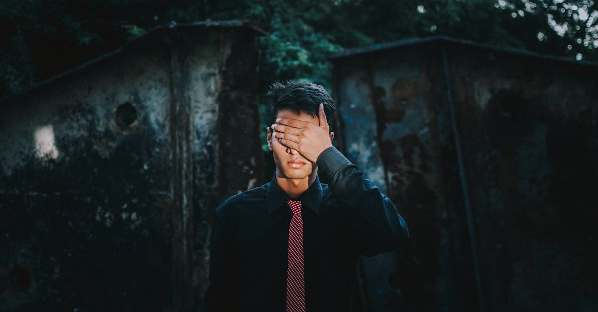 Homem de camisa social e gravata cobrindo os olhos com a mão em um ambiente sombrio. — Foto: Fuzail Ahmad