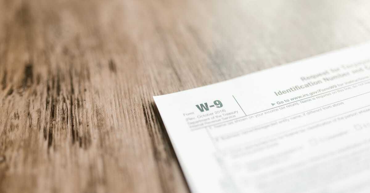 Papel com texto 'W-9' sobre mesa de madeira, relacionado a assuntos fiscais. — Foto: RDNE Stock project