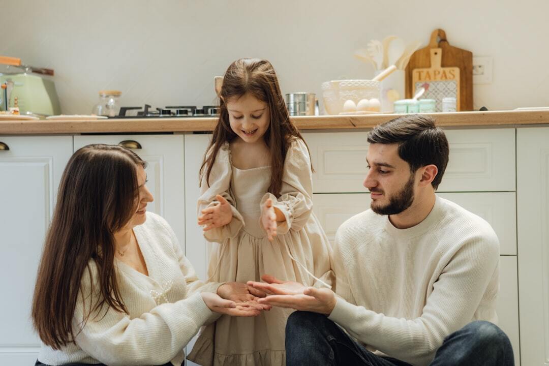 Pai, mãe e filha pequena interagindo de forma carinhosa em uma cozinha. — foto: seljan salimova