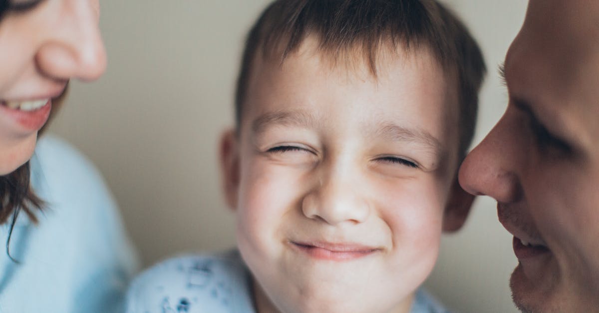 Close de uma criança sorrindo entre o pai e a mãe, representando uma família unida. — Foto: Elina Fairytale