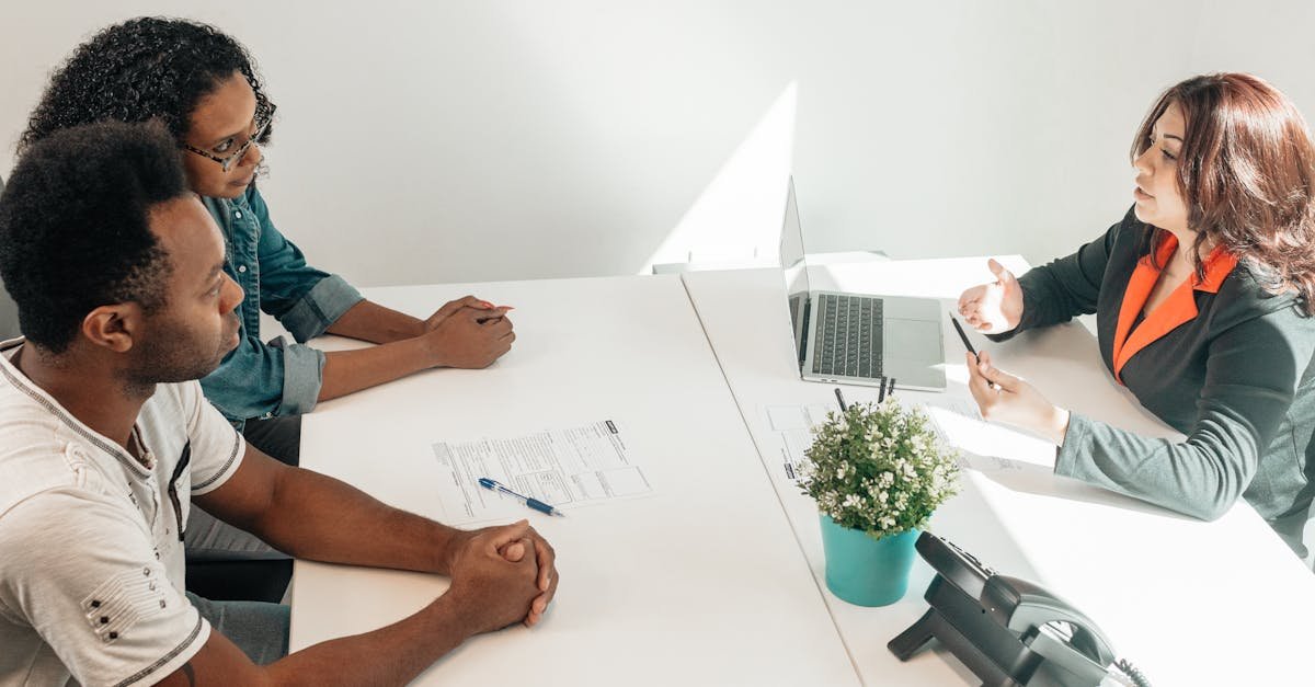 Advogada em reunião com casal em um escritório, discutindo documentos sobre uma mesa branca. — Foto: Kindel Media