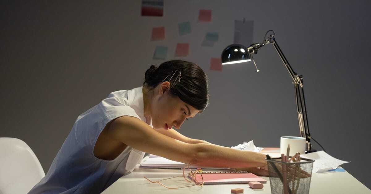 Mulher concentrada em trabalho em mesa com lampada e documentos. — Foto: cottonbro studio