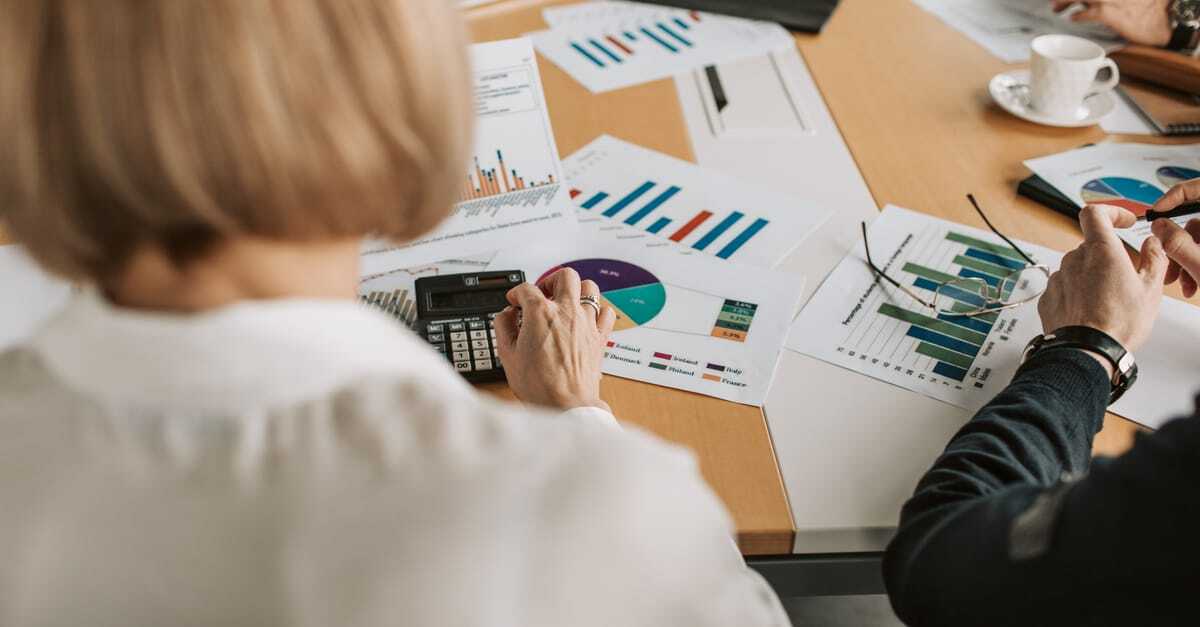 Profissionais analisando gráficos e documentos financeiros em uma reunião de trabalho. — Foto: Vlada Karpovich