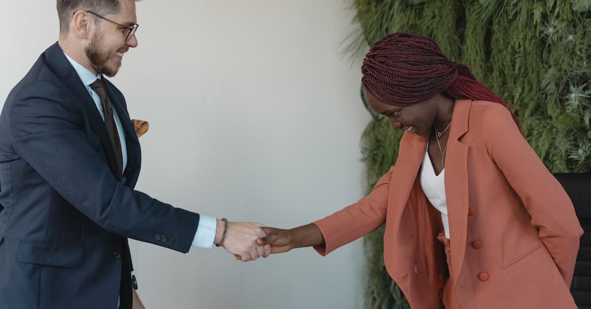 Homem e mulher em trajes profissionais apertando mãos, sugerindo um acordo ou reunião de negócios. — Foto: Tima Miroshnichenko